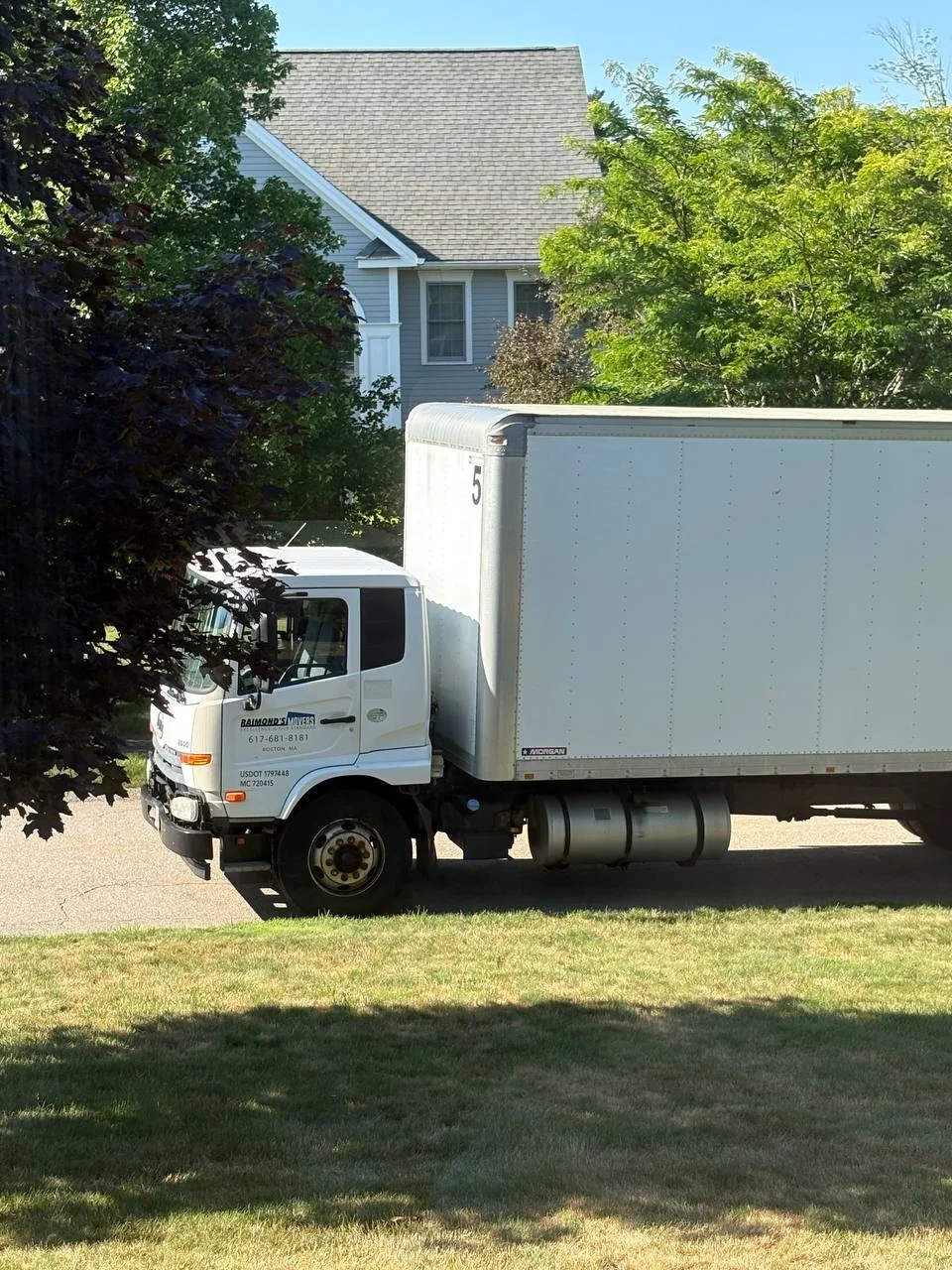 Raimond's Movers branded truck parked near a Cambridge-area home, with phone number and USDOT number visible
