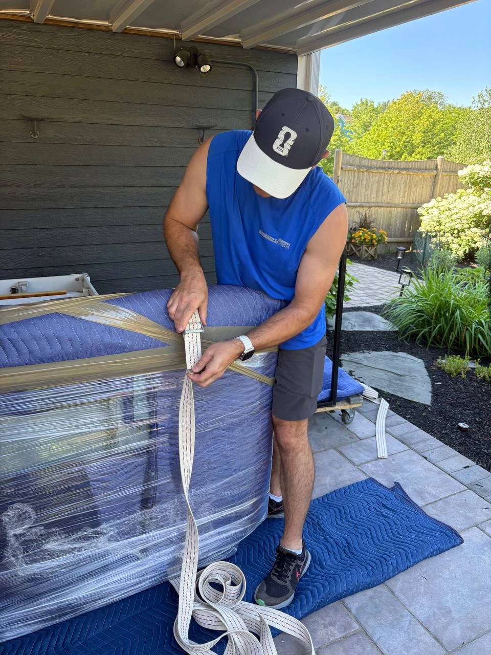 A Raimond's Movers team member securely strapping a wrapped mattress before loading it for a move