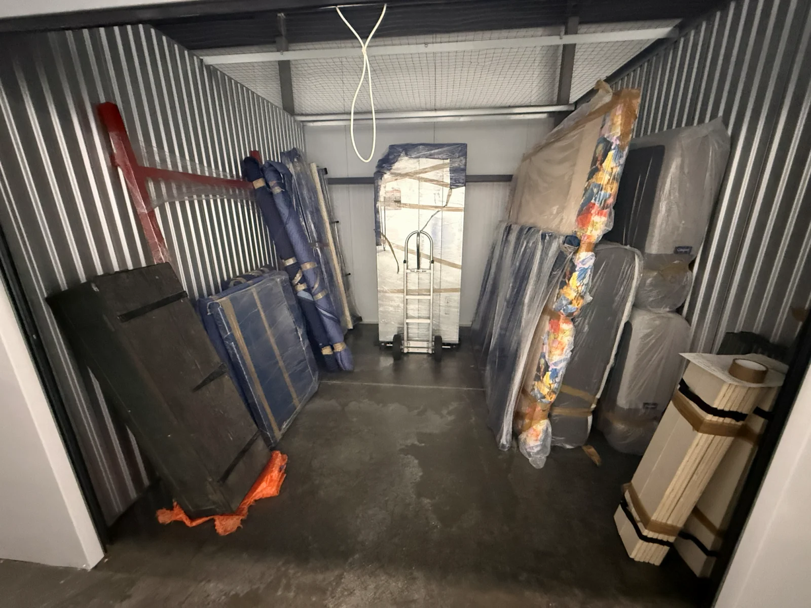 Furniture and mattresses carefully wrapped and organized inside a Raimond's Movers storage unit